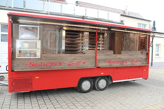 Roter Imbisswagen mit geöffnetem Verkaufsfenster, Schriftzug 'Neuburger's Grill' auf Holzverkleidung