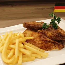 Gebratenes Hähnchen mit Pommes Frites auf weißem Teller, garniert mit Petersilie und deutscher Flagge